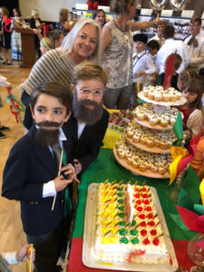 Mokyklos direktorė Marytė Newsom su ketvirtokais Deiviu Danovitch (J. Basanavičius) ir Povilu Gaidžiu (A. Smetona) pasiruošę pjauti šventinį tortą.