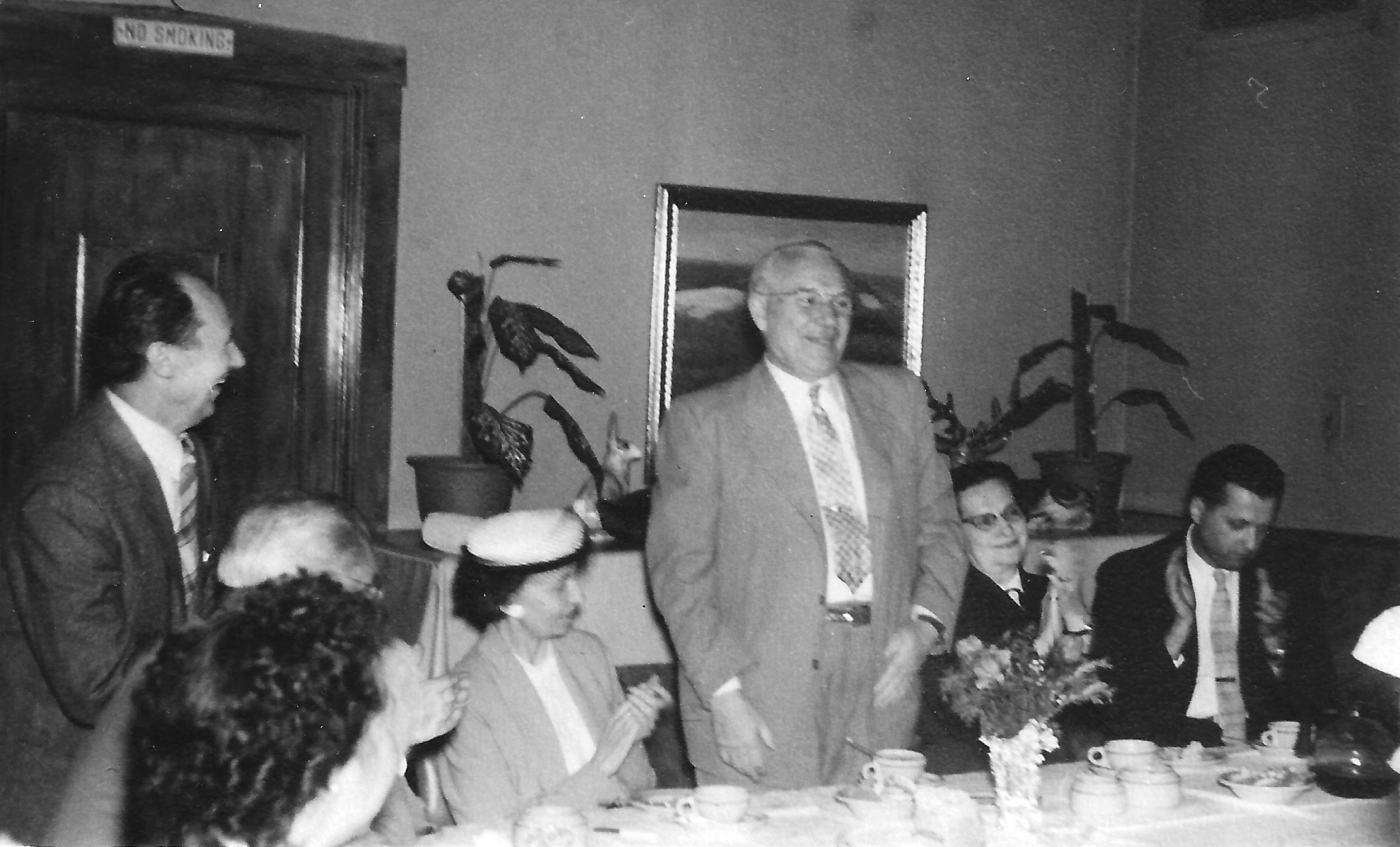 Frank Rakas (v.) praneša apie savo dovaną. Kairėje stovi V. Pavilčius, šalia F. Rako sėdi Milda Budrienė, kitoje pusėje Biežienė ir Stasys Budrys.