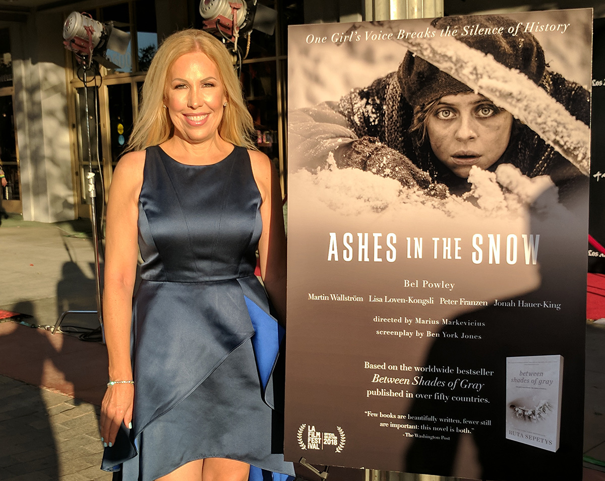 LR garbės konsulė Daiva Navarrette prie „Ashes in the snow" plakato.